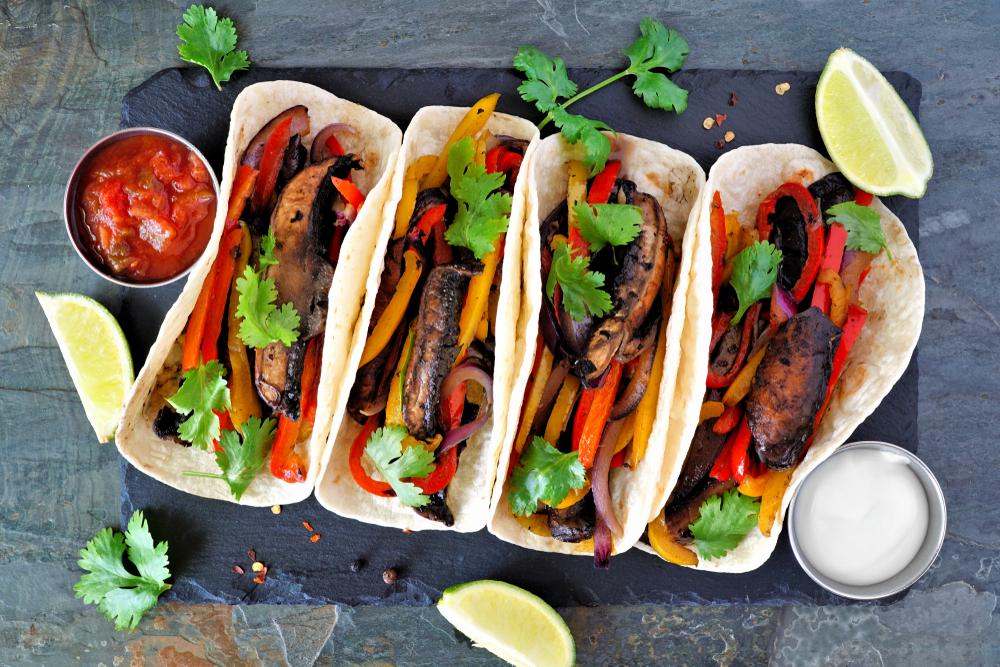 Four tortillas filled with mushrooms and peppers on a grey slate with two sauces in an article about .restaurants in Minneapolis