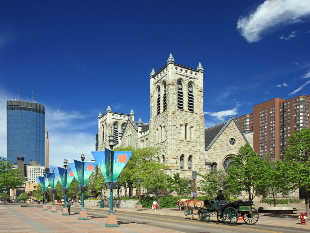 Nicollet Street in downtown Minneapolis with a church, tall building a road with a horse and cart on. Best things to do in Minneapolis MN