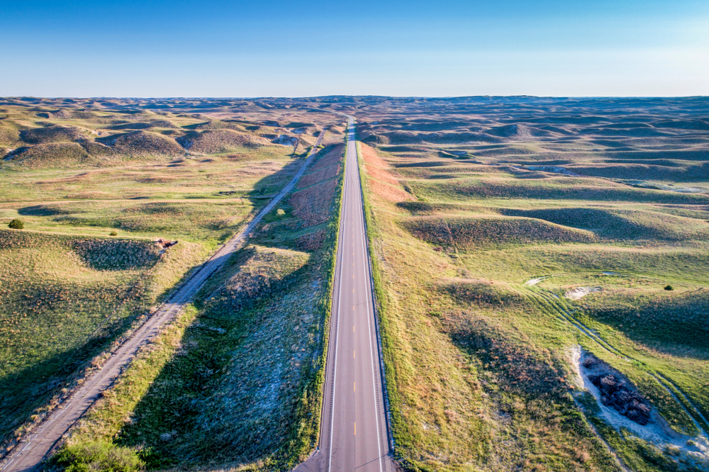 Straight road with plains and greenery on both sides