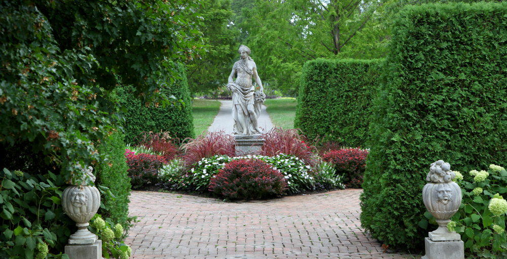 A statue on a path surrounded by foliage and hedges