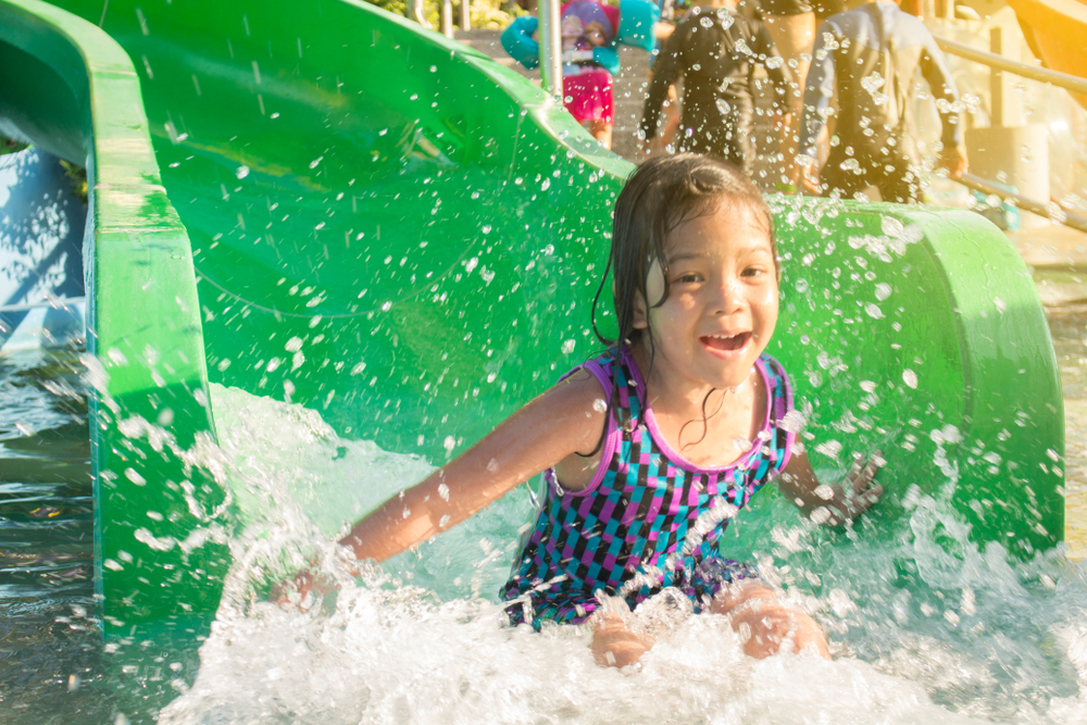 A girl coming down a green waterslide.