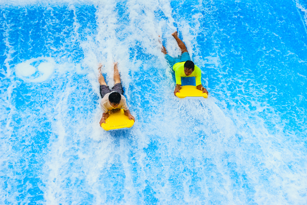 Two kids body surfing at a waterpark.