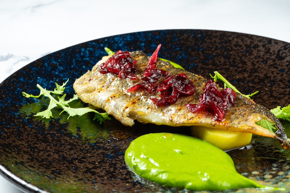 Grilled fish on a plate with a green sauce