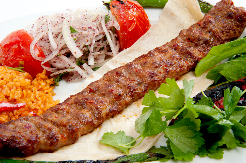 A piece of kebab meat on a plate with vegetables and flatbread in an article about Restaurants in Milwaukee