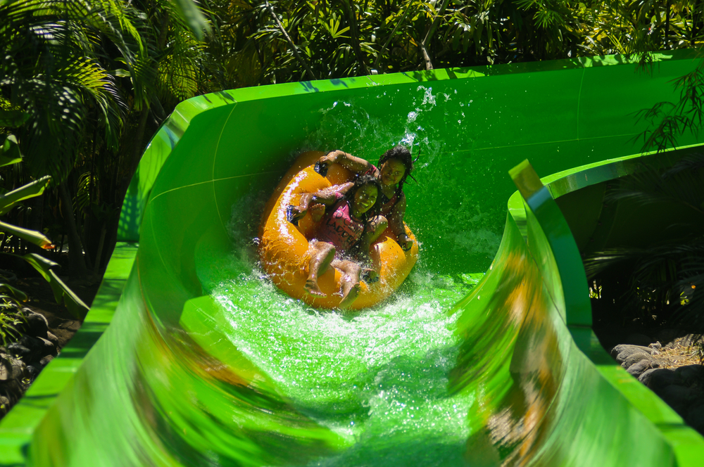 Two people going down a green waterslide. one of the cool waterparks in Ohio