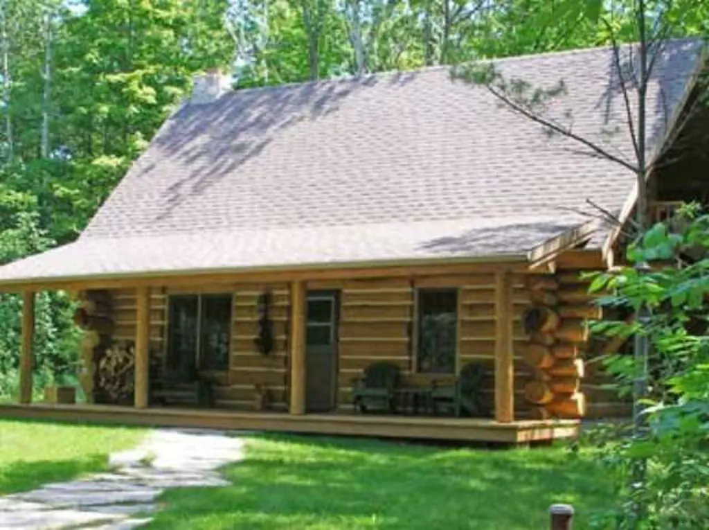 A wooden cabin with a porch surrounded by trees one of the cabins in Door County