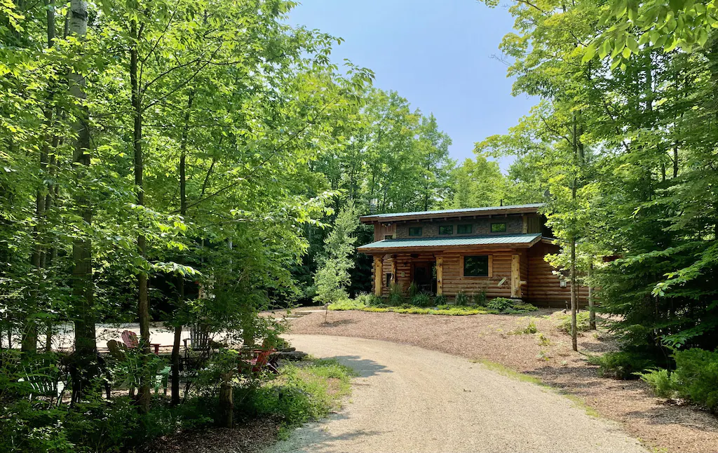 A log cabin in the woods with a road leading to it