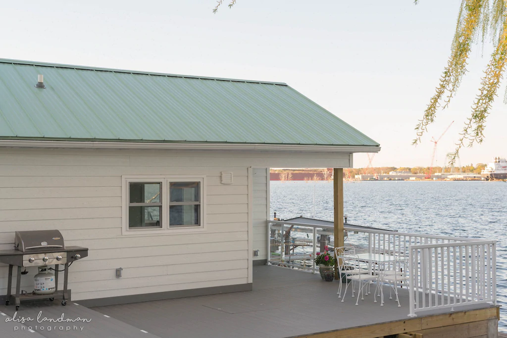 A white cabin over the water with a porch