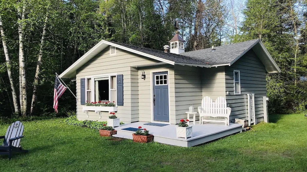 A grey wooden clapboard cottage with a small front porch one of the cabins in Door County