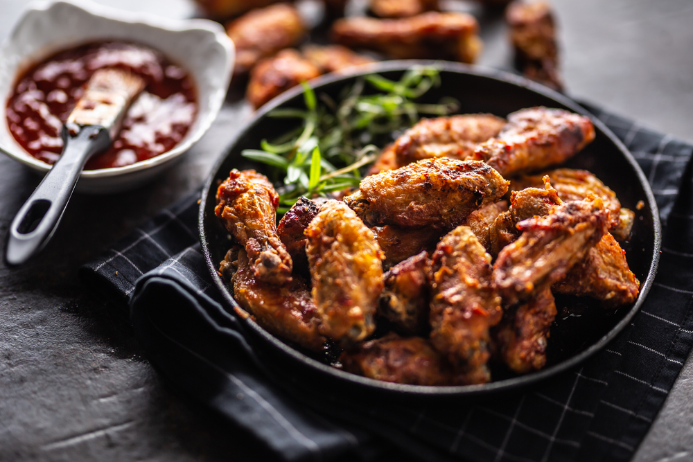 Chicken wings in a black dish on a napkin with a side or sauce