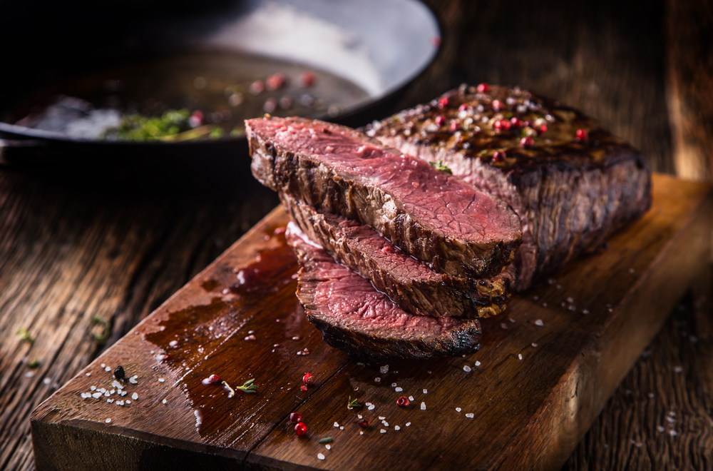 medium beef steak handout on a board and covered in peppercorn in an article about restaurants in Kalamazoo