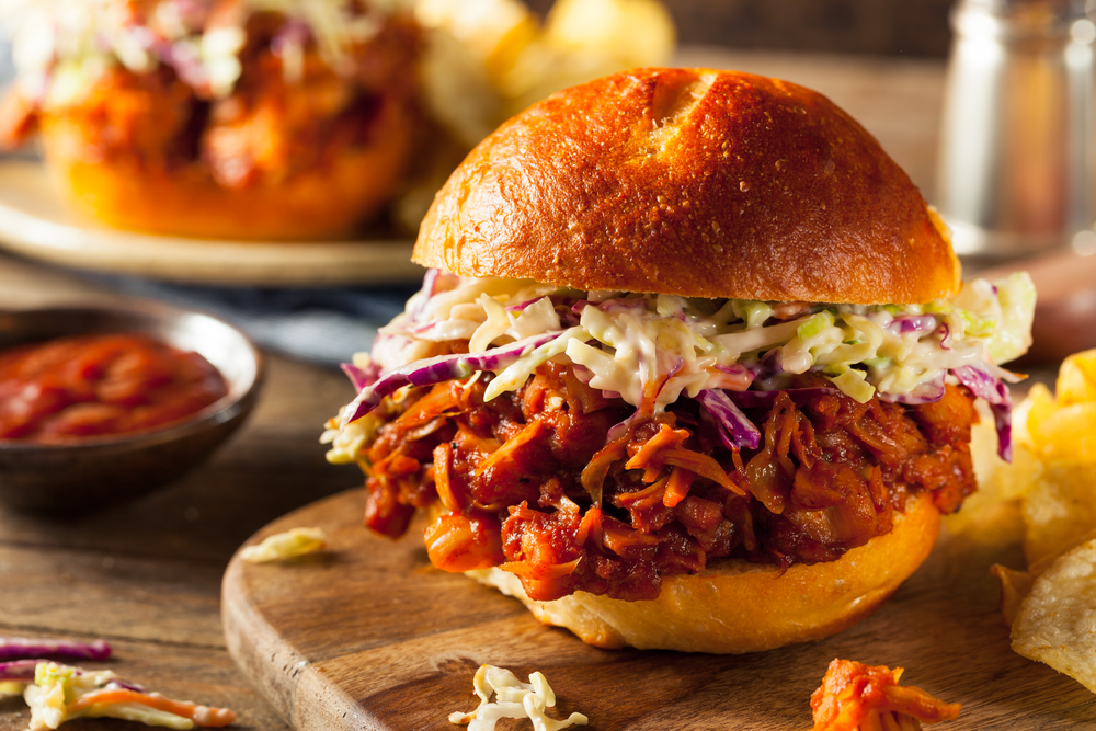 A jackfruit birger overflowing with filling on a wooden board in an article about restaurants in Kalamazoo