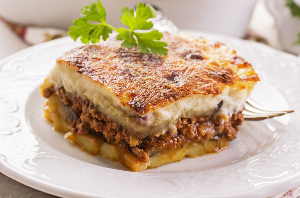 A piece of Moussaka on a white plate at one of the Greek restaurants in Kalamazoo