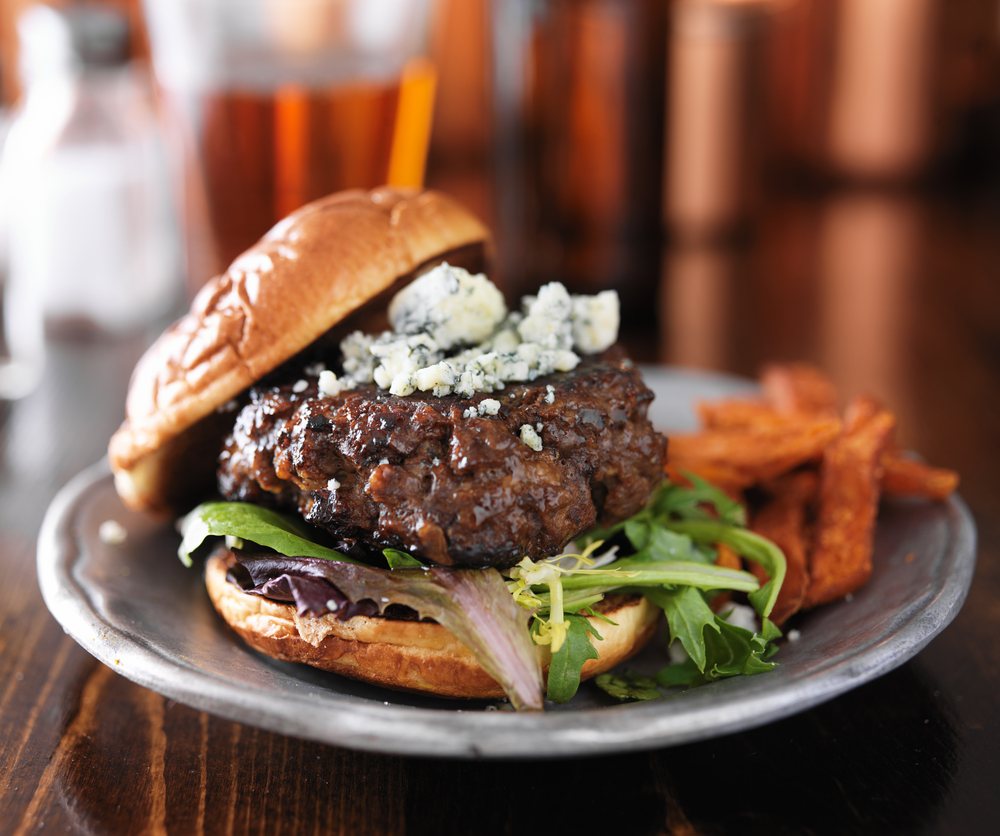 Burger on a plate with fries with blue cheese on top in an article about restaurants in Marquette MI