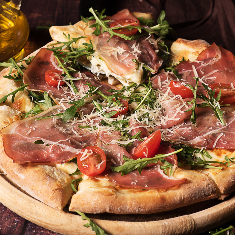 A pizza with tomatoes and rocket and ,Prosciutto