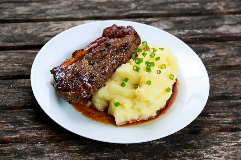 Steak with mashed potatoes on a plate with gravy in an article about restaurants in Marquette MI