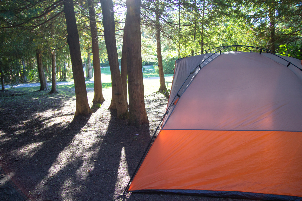 An orange and white tent in the woods of Michigan. One of the best spots for camping in Michigan. 