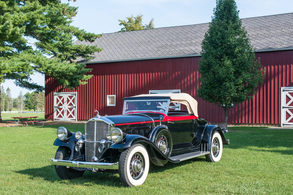 An vintage car in front of a red garage