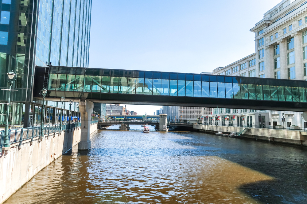 A glass bridge over the water between two large buildings in an article about things to do in Milwaukee