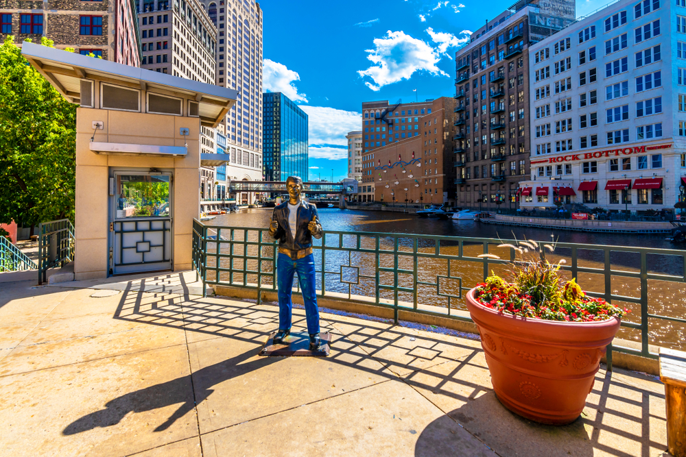 Bronze statue on The Fonz by the river with buildings in the background one of the things to do in Milwaukee