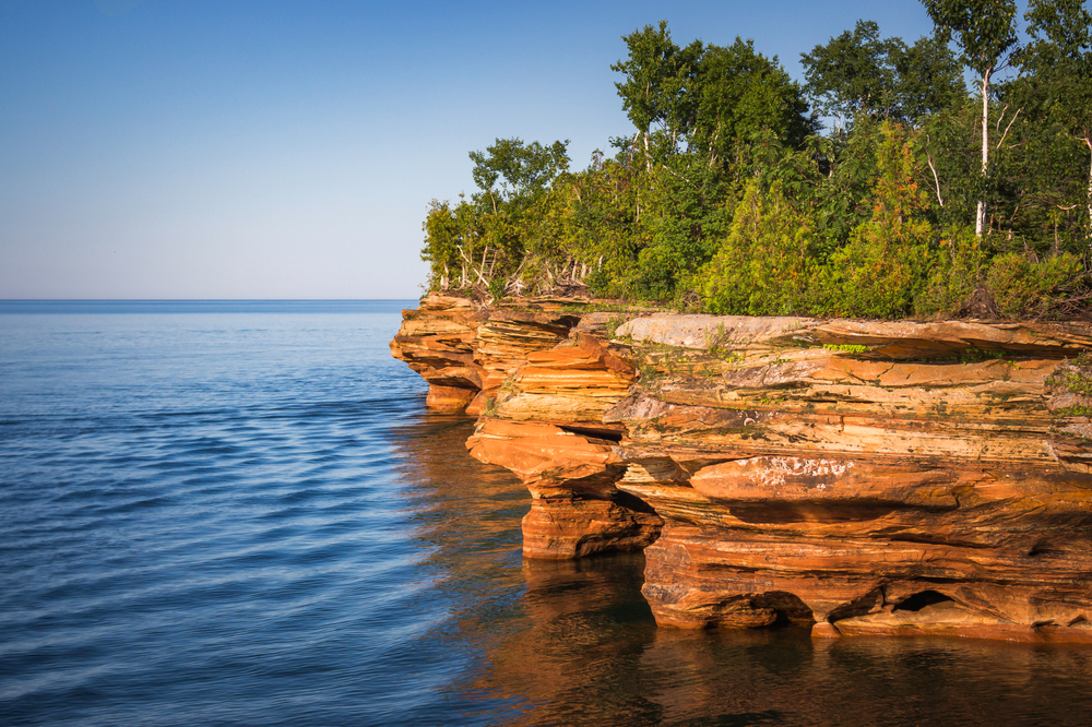 A rocky outcropping on the shores of the Apostle Islands National Lakeshore with beautiful, blue water. This is one of the most famous places to visit in Wisconsin.