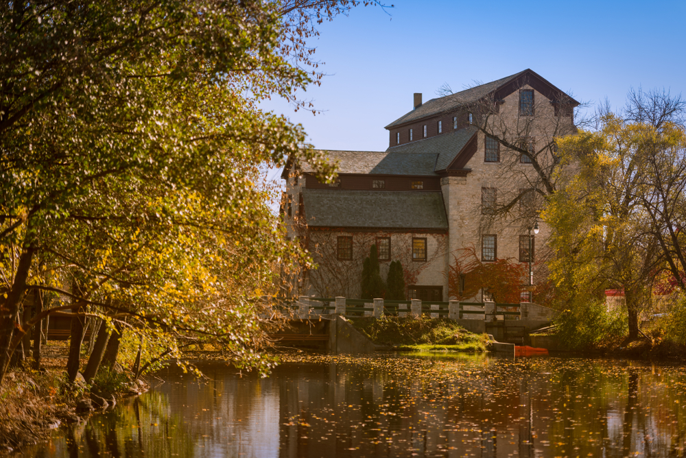 The historic Cedarburg mill overlooking water and surrounded by yellow trees.