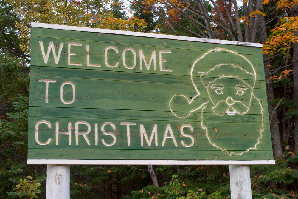 Green sign saying "Welcome to Christmas" with Santa Claus. One of the most unique places to visit in Michigan