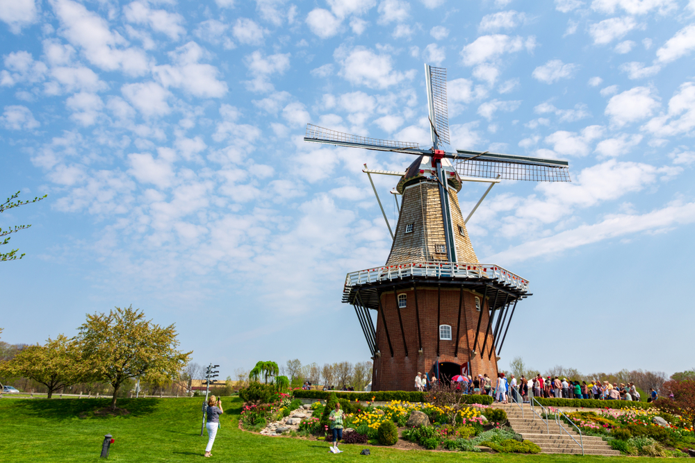 The De Zwaan Windmill standing tall with tourists waiting to go inside, one of the best places to visit in MI..