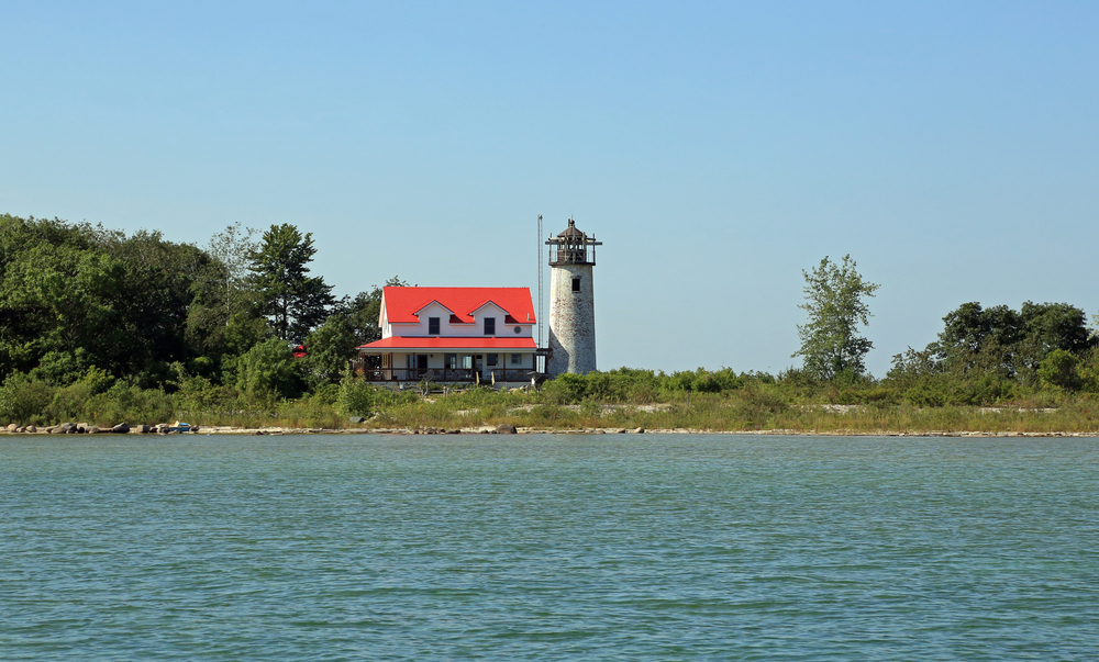 The Charity Island Lighthouse next to trees as seen across the lake.