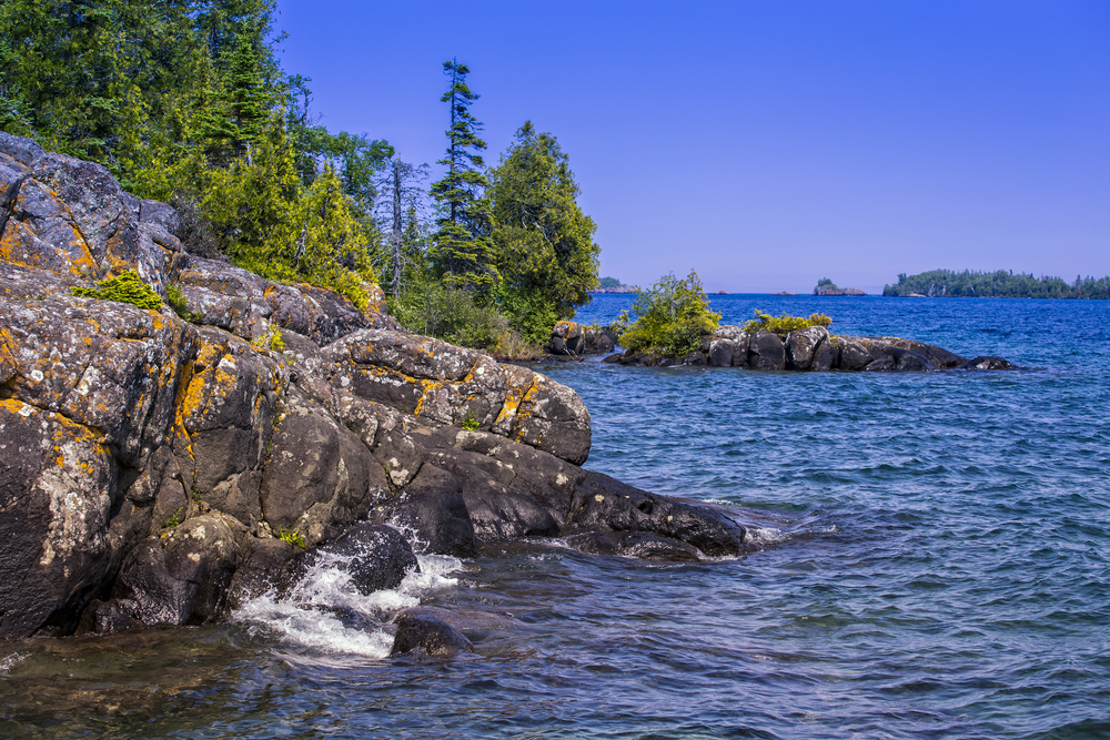 Rough rocks and pretty, blue water at Isle Royale National Park. One of the most beautiful places to visit in Michigan.