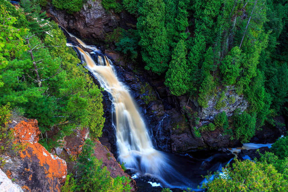 Aerial view of Big Manitou Falls flowing down among green trees.