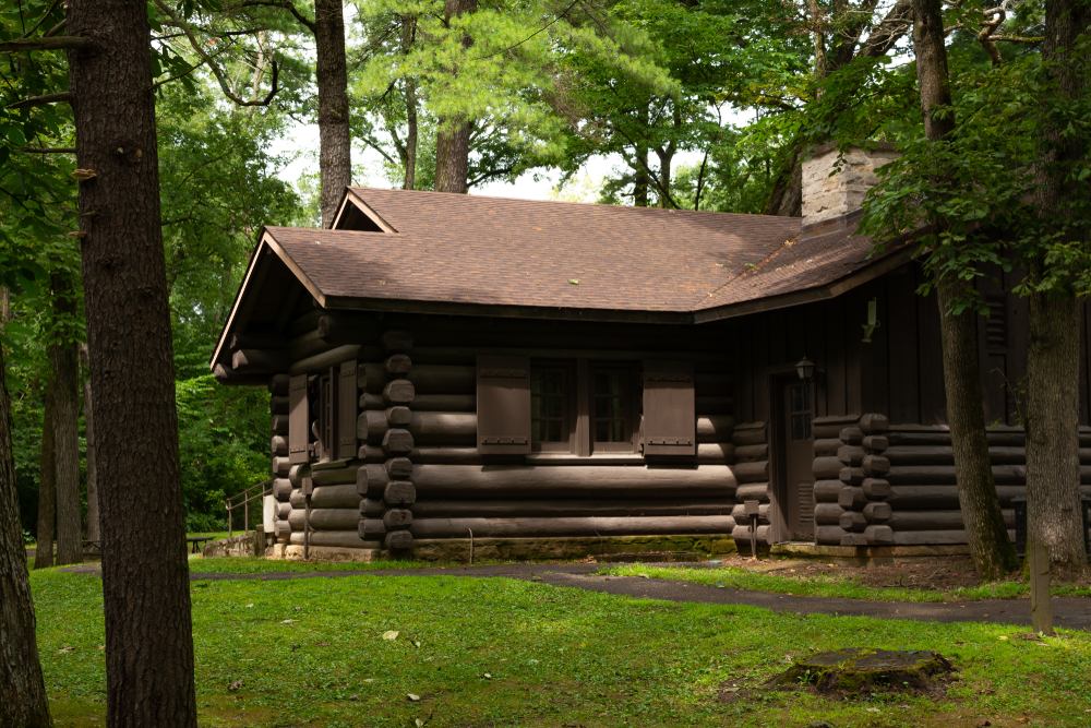A large log cabin surrounded by grass and trees where you can go camping in Ohio.