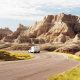 An RV driving down the road through the rock formations in Badlands National Park. One of the best places for camping in South Dakota