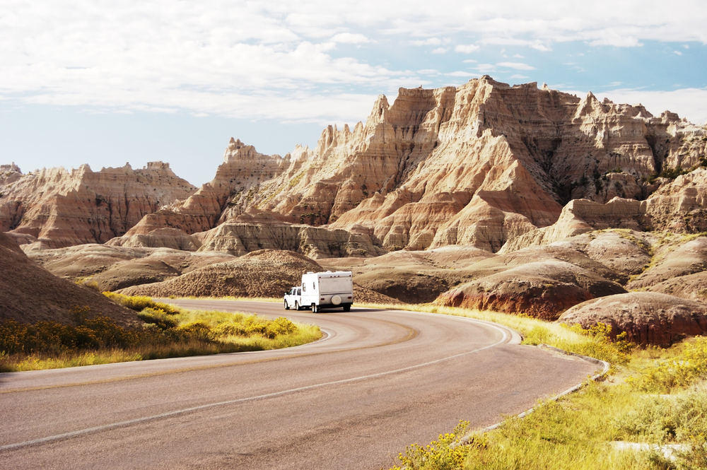 An RV driving down the road through the rock formations in Badlands National Park. One of the best places for camping in South Dakota. 