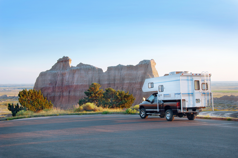 An RV parked at a scenic look out at some of the Black Hills formations on a sunny day. 