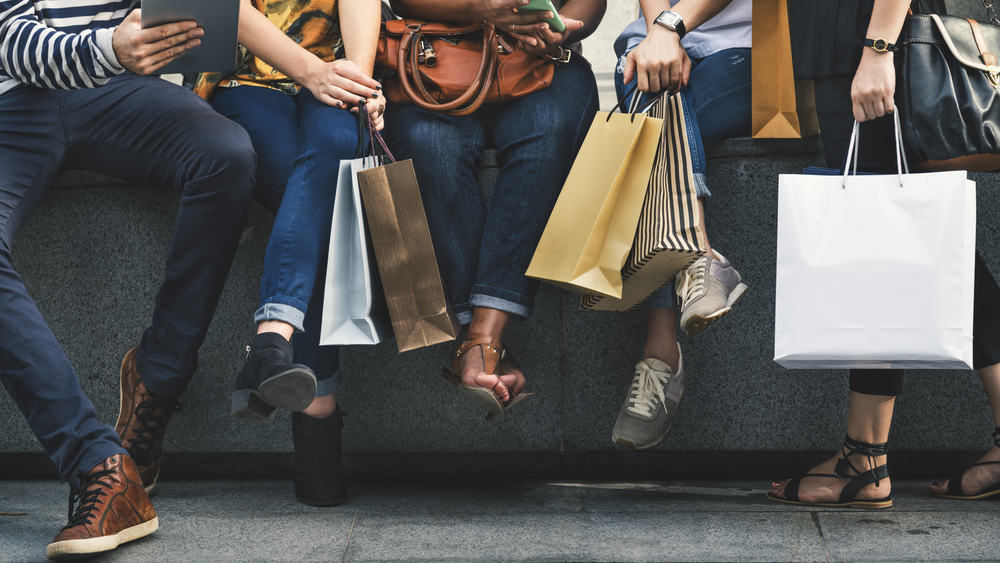 A group of people sitting down with shopping bags