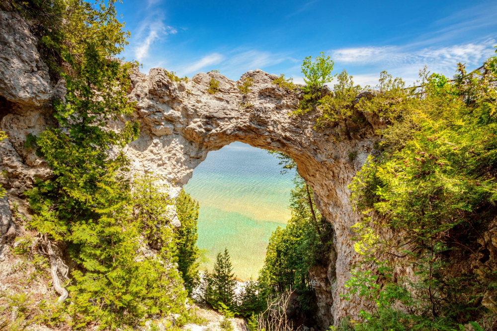 View of Arch Rock with lots of greenery at golden hour with the lake in the distance.
