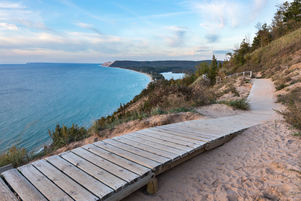 wooden boardwalk alongside large blue lake and sand. Best of Michigan hiking