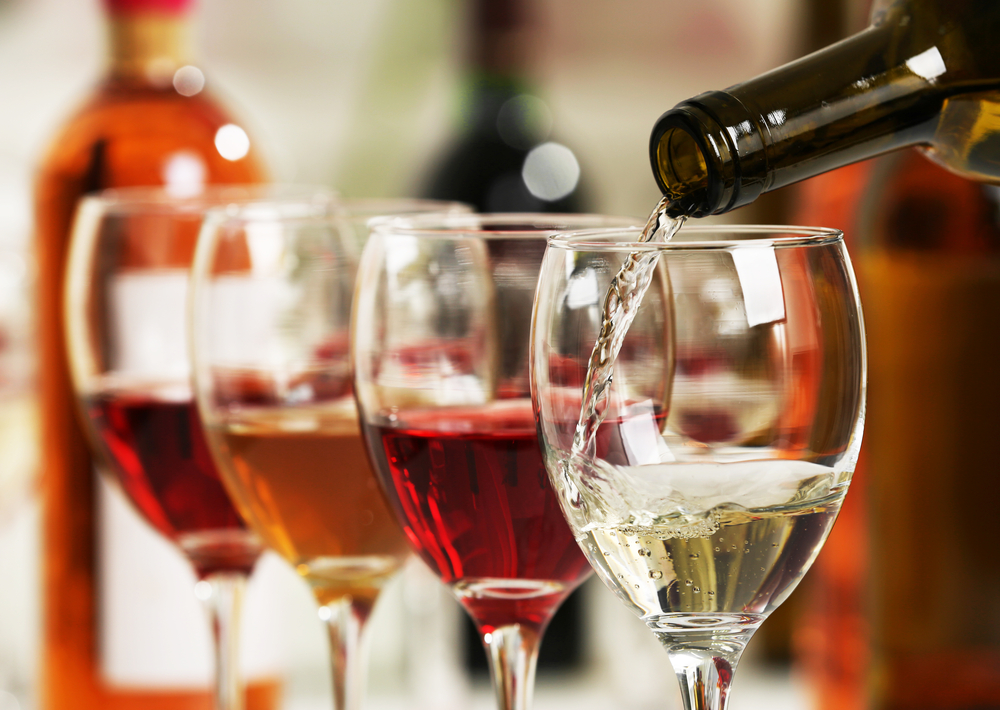 Detail shot of white wine being poured into a glass with more glasses in the background.