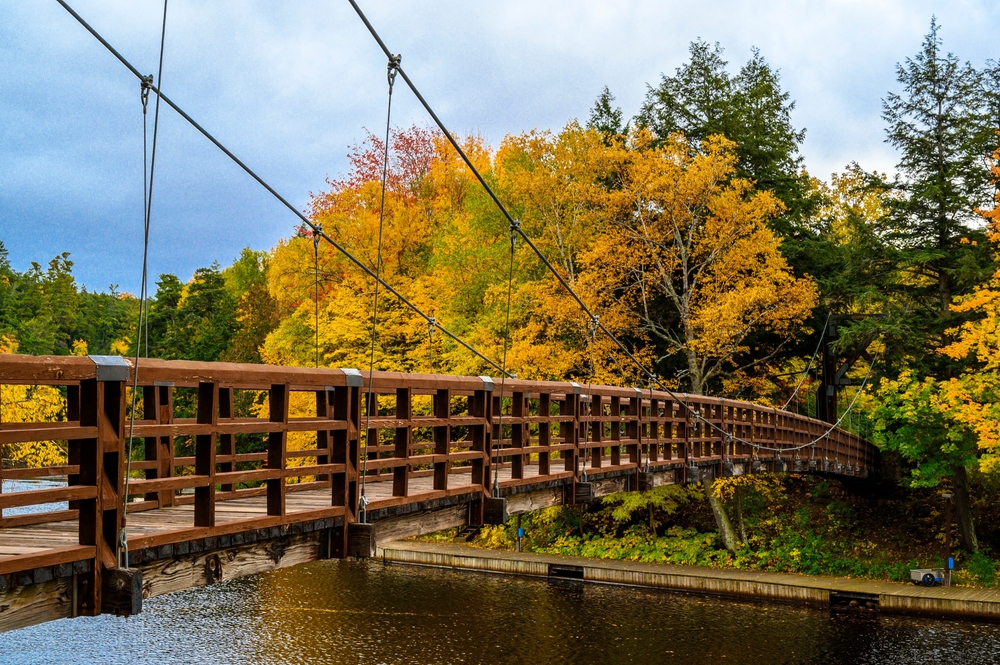 A bridge spanning a river during fall on the Iron Belle Trail, some of the best hiking in Michigan.