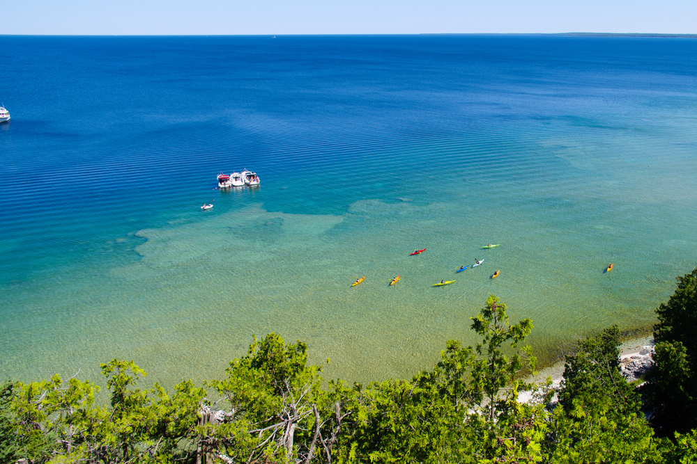 Looking down at a group of kayaks and boats in the water along Mackinac Island.