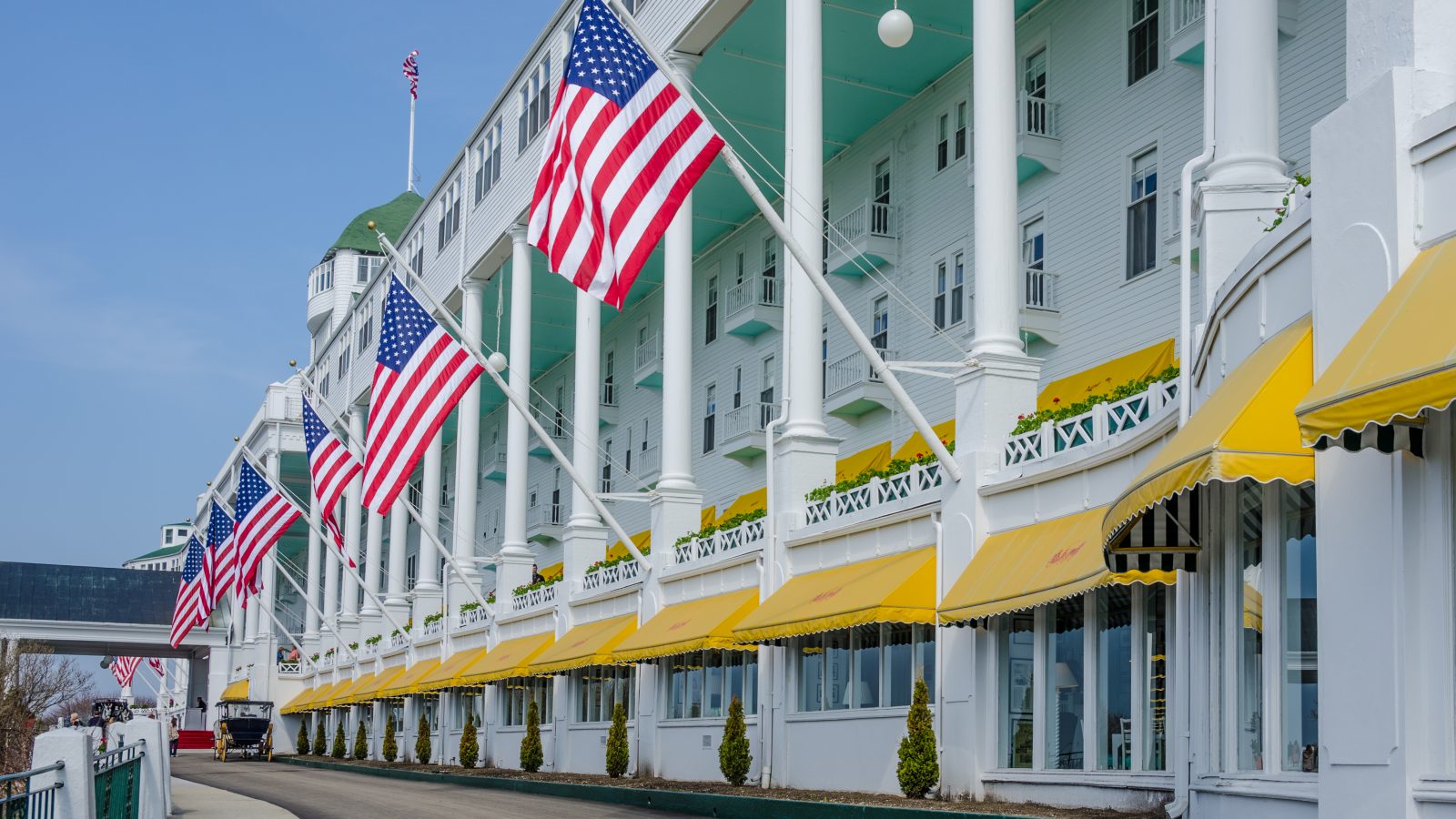 Hotel with white pillars, yellow awnings, and American flags