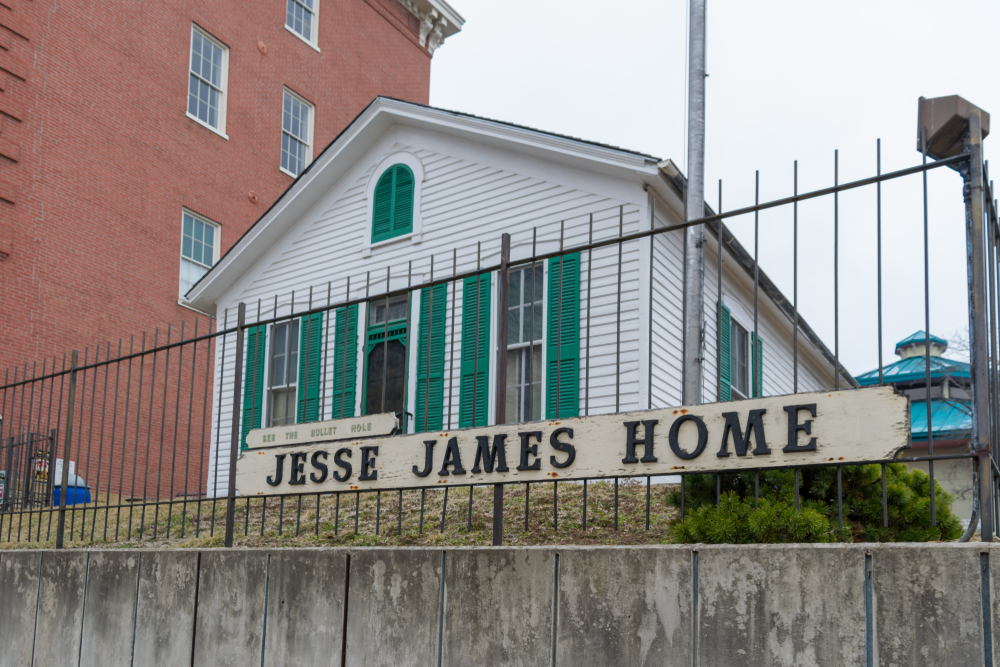 The white Jesse James Home behind an iron fence.