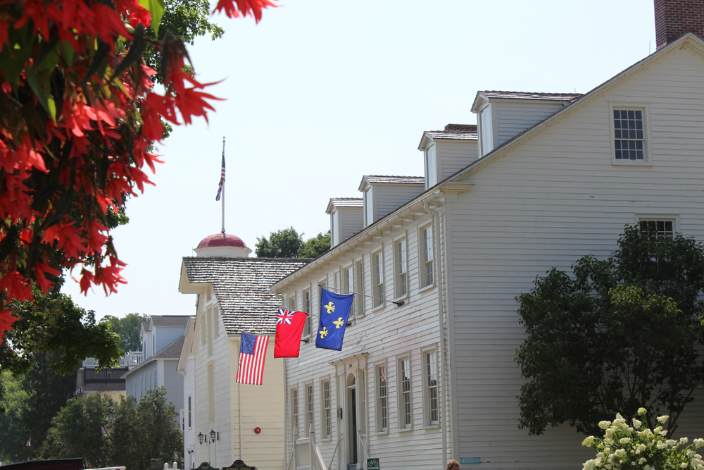 Side view of the white Stuart House City Museum with flags hanging in front.