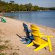 Two comfy Adirondack shairs, one blue and one yellow sitting on sandy Door County WI beach.