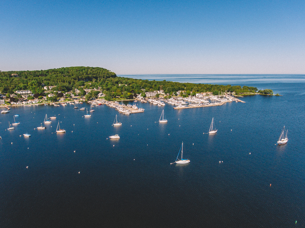 The bay of Fish Creek with the harbour and boats in the sea and trees in the background. 