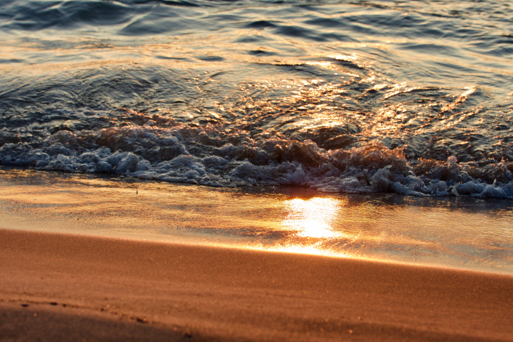 Waves breaking on the beach with a reflection of the sunrise 