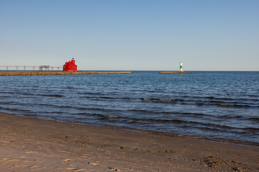 Beach with a red lighthouse in the distance in an article about beaches in Door County  