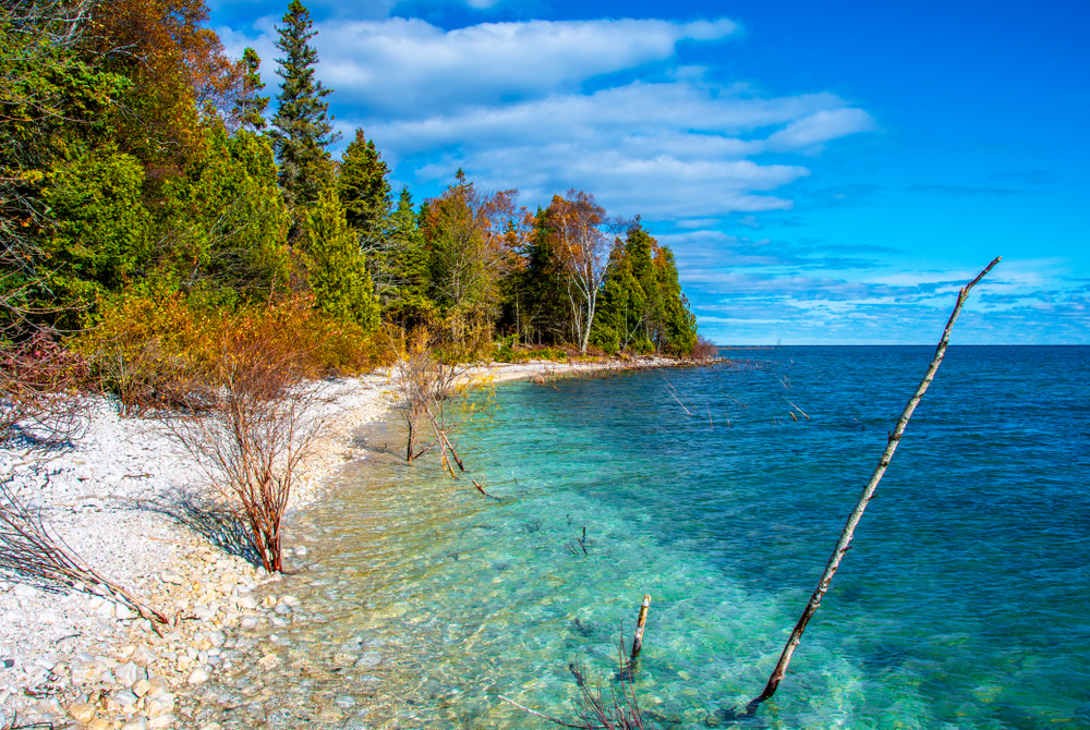 Beautiful blue water and a rock shore with trees in the background one of the beaches in Wisconsin