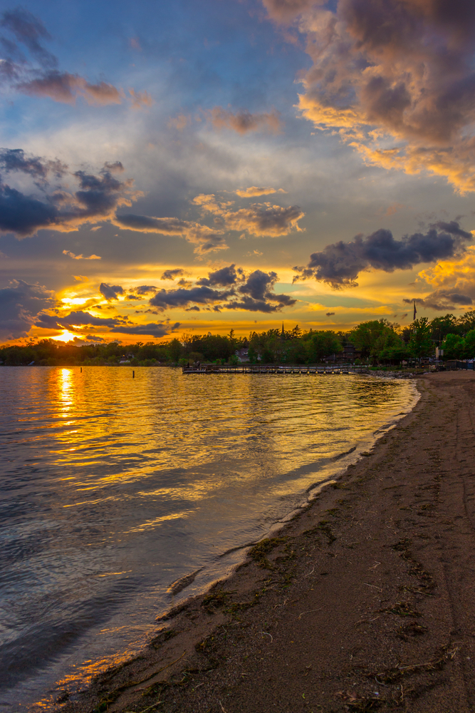 sunset over Pewaukee one of the beaches in Wisconsin with trees in the background